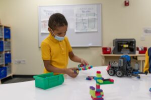 An Indy STEAM Academy student in a school uniform explores the engineering process with materials in a classroom