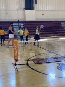  Indy STEAM Academy students participate in tennis drills with a tennis instructor in the gymnasium