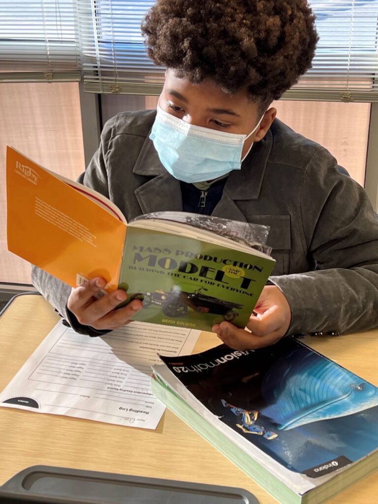 An Indy STEAM Academy student reads a book at his desk.