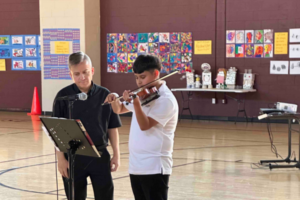 An Indy STEAM Academy student performs the violin with his instructor at his side.