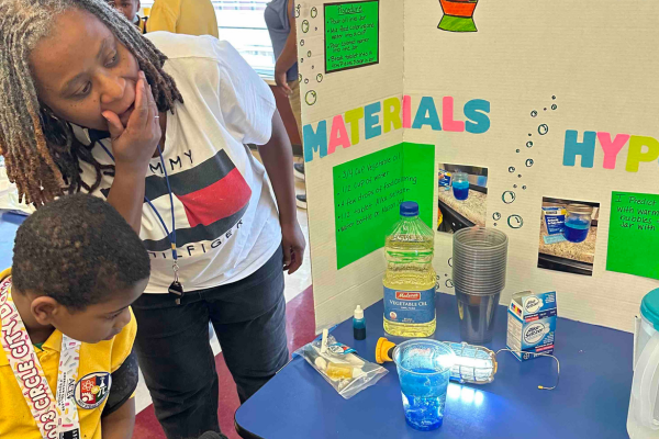 IndySTEAM Academy educator and students present a lava lamp STEM project at a science fair.