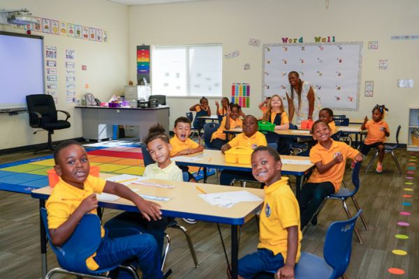 IndySTEAM Academy students smile in class, wearing their matching yellow shirts.
